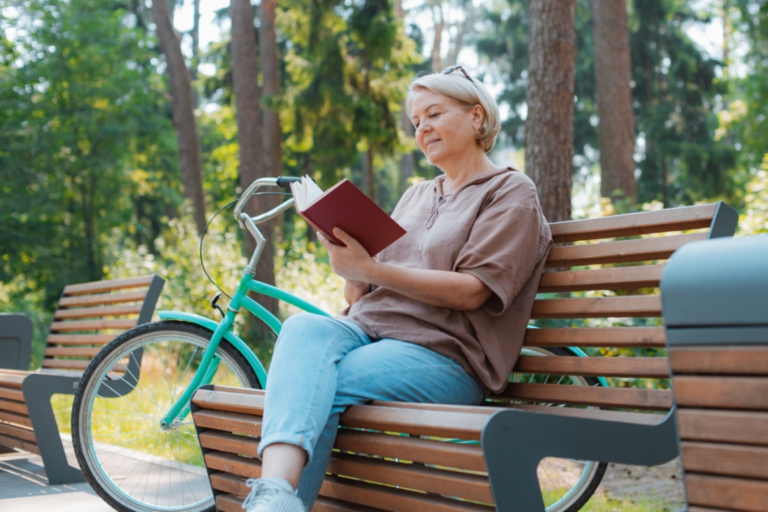 middle age woman relaxing on a park bench with a book